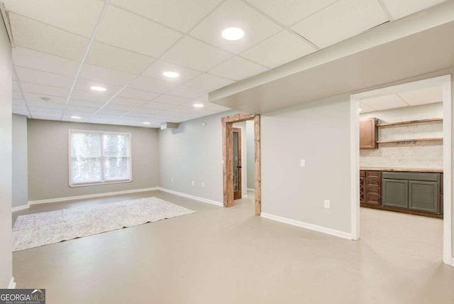 below grade area with recessed lighting, a paneled ceiling, and baseboards