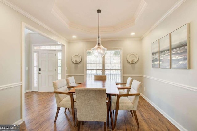 dining area featuring wood finished floors, baseboards, recessed lighting, ornamental molding, and a raised ceiling