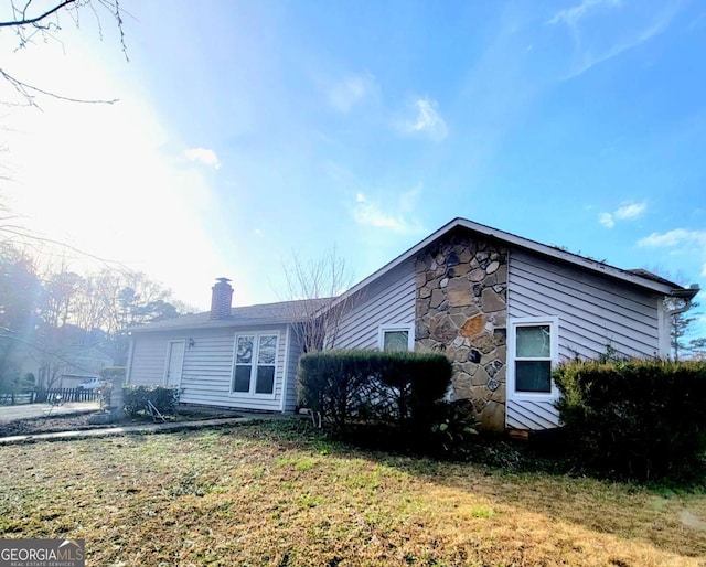 view of side of home featuring stone siding and a chimney