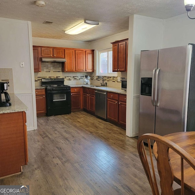 4906 Kellys Mill Dr NW, Lilburn, GA 30047 - kitchen with stainless steel appliances, under cabinet range hood, dark wood-type flooring, a textured ceiling, and decorative backsplash