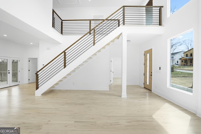 foyer entrance featuring a high ceiling, french doors, wood finished floors, and a wealth of natural light