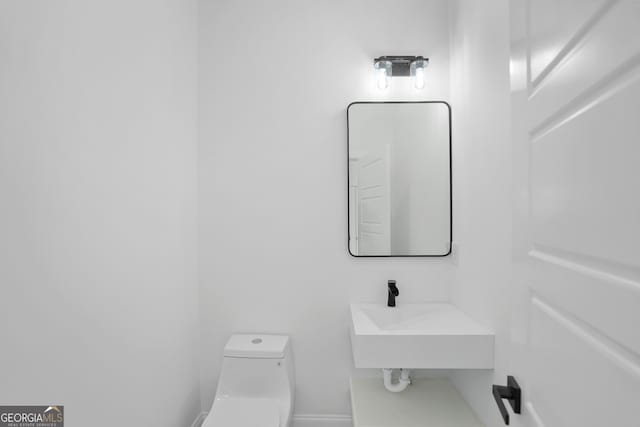 bathroom with a sink, baseboards, and toilet