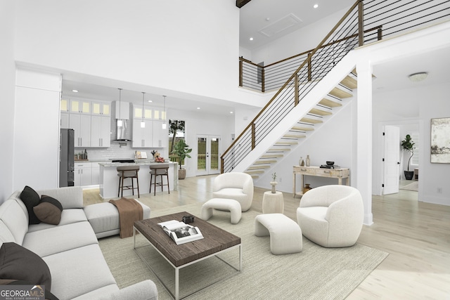 living area with recessed lighting, a towering ceiling, stairs, and light wood finished floors