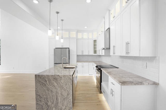 kitchen with a sink, stainless steel appliances, light wood-type flooring, and white cabinetry