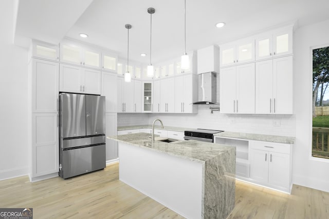 kitchen with light wood-style flooring, stainless steel appliances, wall chimney range hood, and a sink