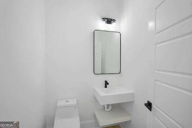 bathroom featuring a sink, baseboards, and toilet