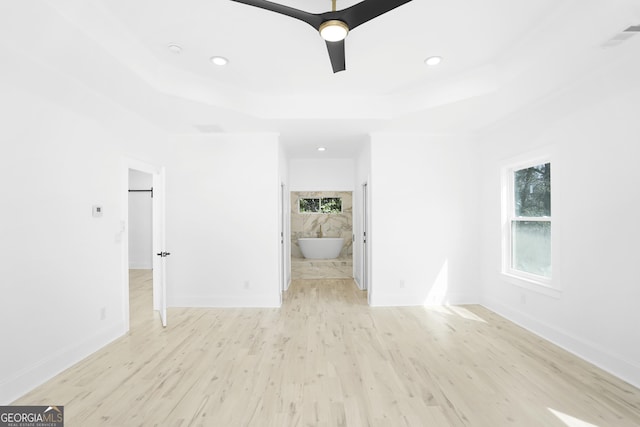 empty room with recessed lighting, a raised ceiling, baseboards, and wood finished floors