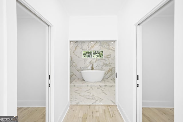 hall with wood finished floors, baseboards, and ornamental molding