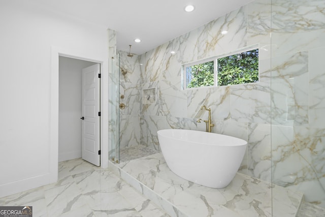 full bath featuring marble finish floor, recessed lighting, a marble finish shower, a freestanding bath, and stone wall