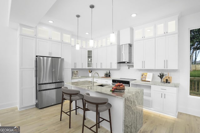 kitchen with tasteful backsplash, range with electric stovetop, freestanding refrigerator, wall chimney exhaust hood, and a sink