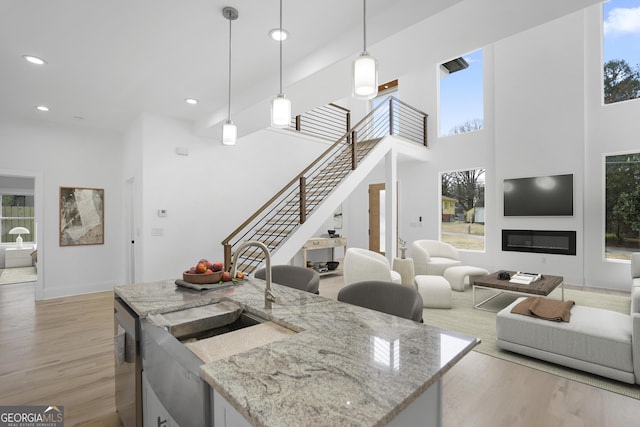 kitchen featuring a sink, light wood-type flooring, stainless steel dishwasher, and a glass covered fireplace