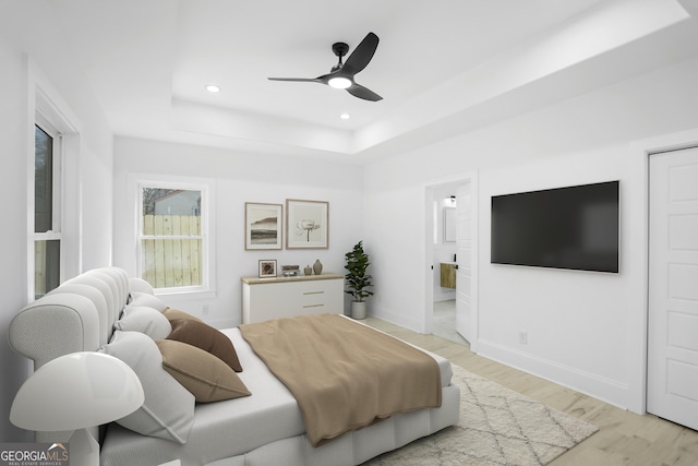 bedroom with a raised ceiling, recessed lighting, light wood-style floors, baseboards, and ceiling fan