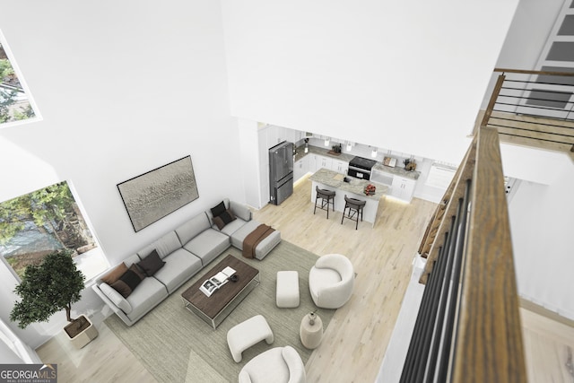 living area with light wood-type flooring and a towering ceiling