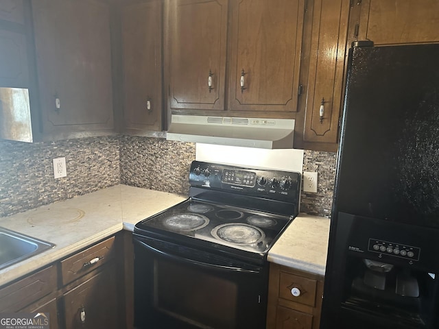 kitchen featuring under cabinet range hood, light countertops, decorative backsplash, black appliances, and a sink