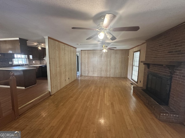 unfurnished living room with hardwood / wood-style flooring, crown molding, a fireplace, and a textured ceiling