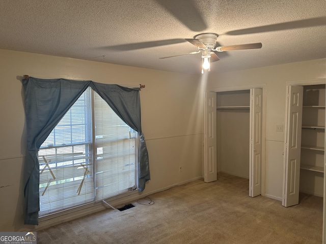 unfurnished bedroom with visible vents, light carpet, and a textured ceiling