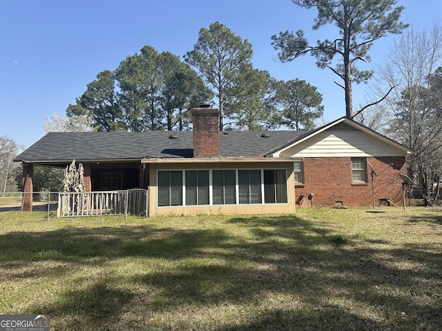 rear view of property featuring a yard, a sunroom, a chimney, crawl space, and brick siding