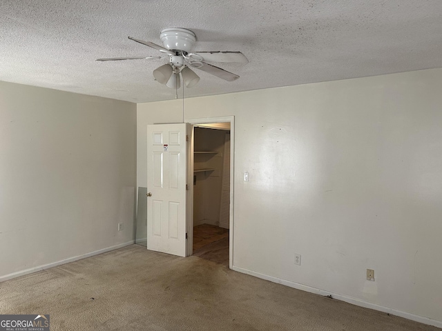 unfurnished bedroom featuring a walk in closet, baseboards, carpet, a closet, and a textured ceiling