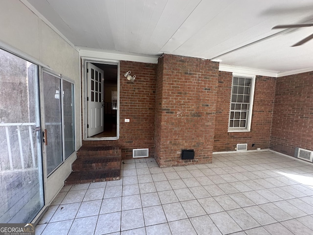 spare room with light tile patterned floors, visible vents, brick wall, and ceiling fan