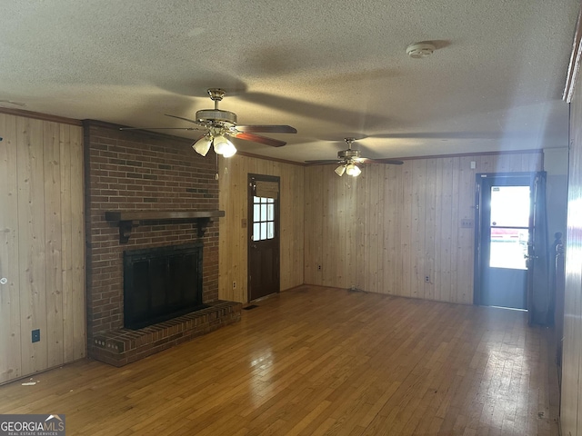 unfurnished living room featuring plenty of natural light, a brick fireplace, and wood-type flooring