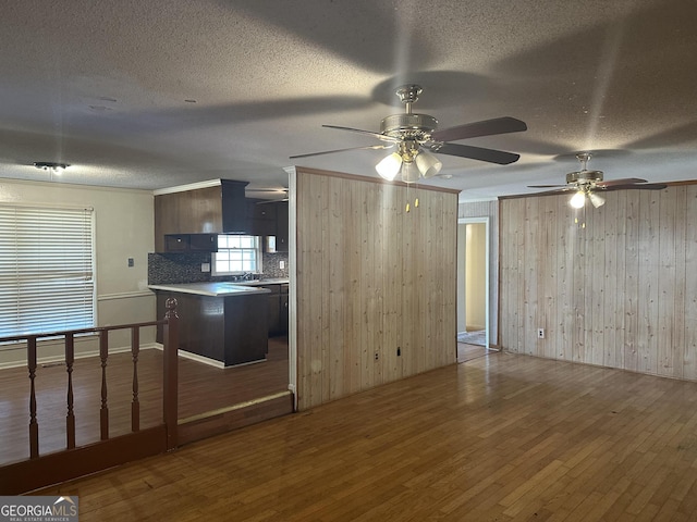 kitchen featuring tasteful backsplash, a textured ceiling, hardwood / wood-style floors, and wooden walls