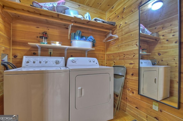 laundry room featuring wooden walls, washing machine and dryer, and laundry area