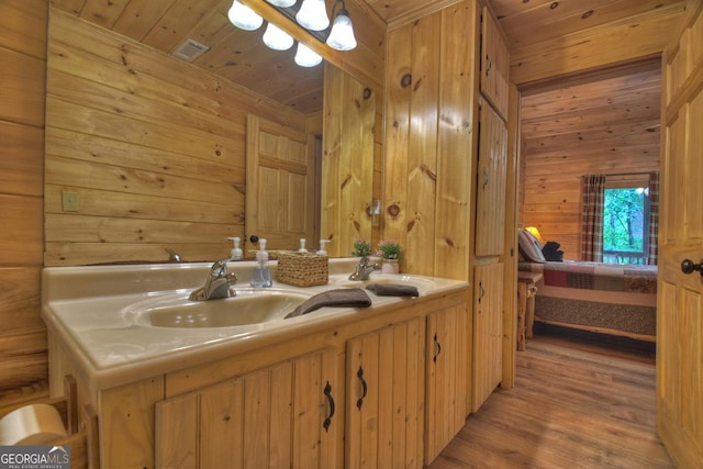 bathroom featuring wooden ceiling, wooden walls, wood finished floors, and a sink