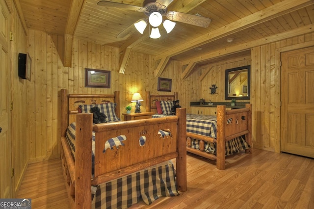 bedroom featuring beam ceiling, wood ceiling, wood finished floors, and wood walls