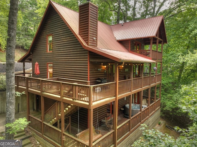 rear view of property with a wooden deck, a chimney, and metal roof