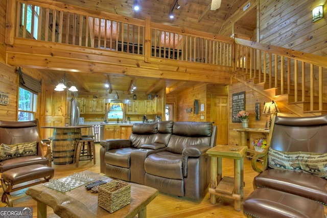 living area featuring light wood-style flooring, stairway, wooden walls, rail lighting, and wood ceiling