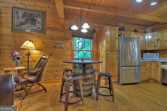 kitchen with beam ceiling, white microwave, light wood-type flooring, and freestanding refrigerator