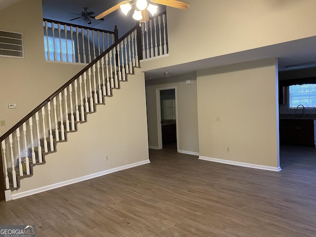 interior space with visible vents, wood finished floors, a towering ceiling, baseboards, and ceiling fan