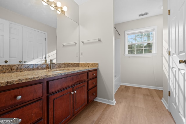 full bathroom featuring visible vents, baseboards, bathing tub / shower combination, wood finished floors, and vanity