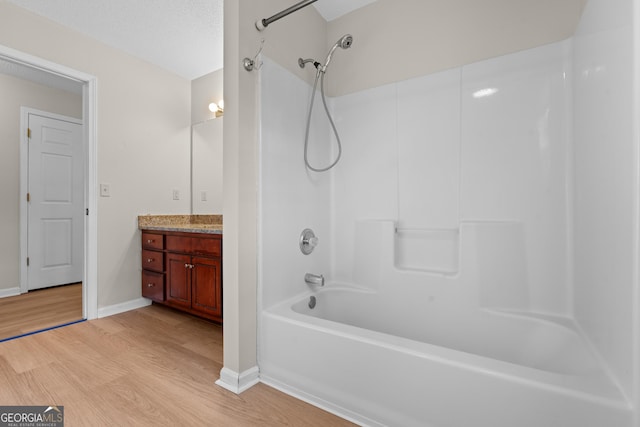 bathroom featuring vanity, washtub / shower combination, wood finished floors, baseboards, and a textured ceiling