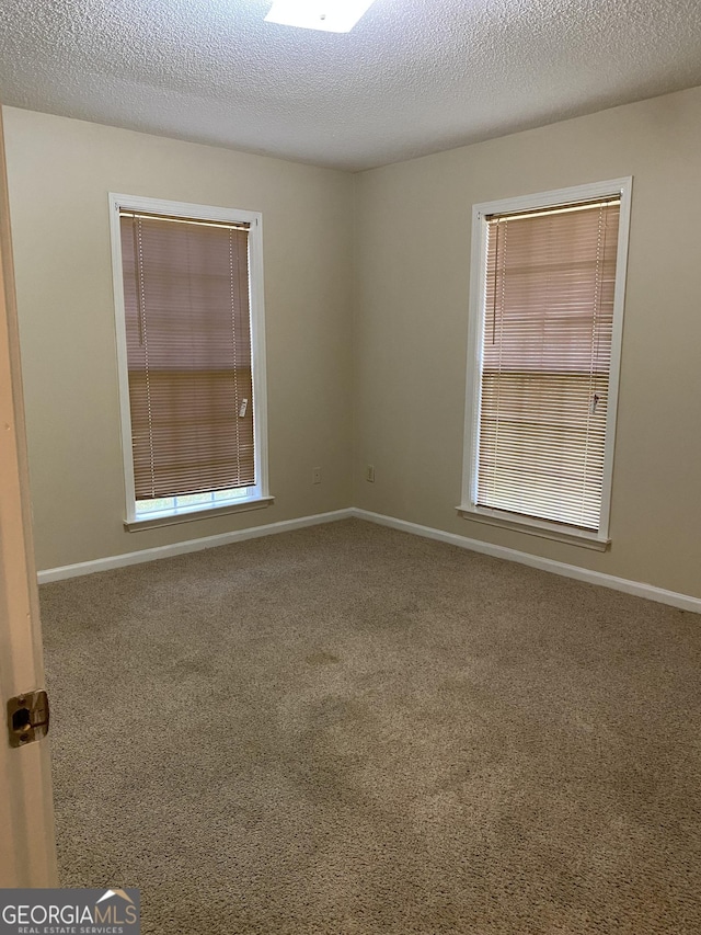 carpeted empty room featuring baseboards and a textured ceiling