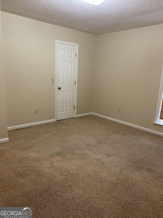 carpeted spare room with baseboards and a textured ceiling