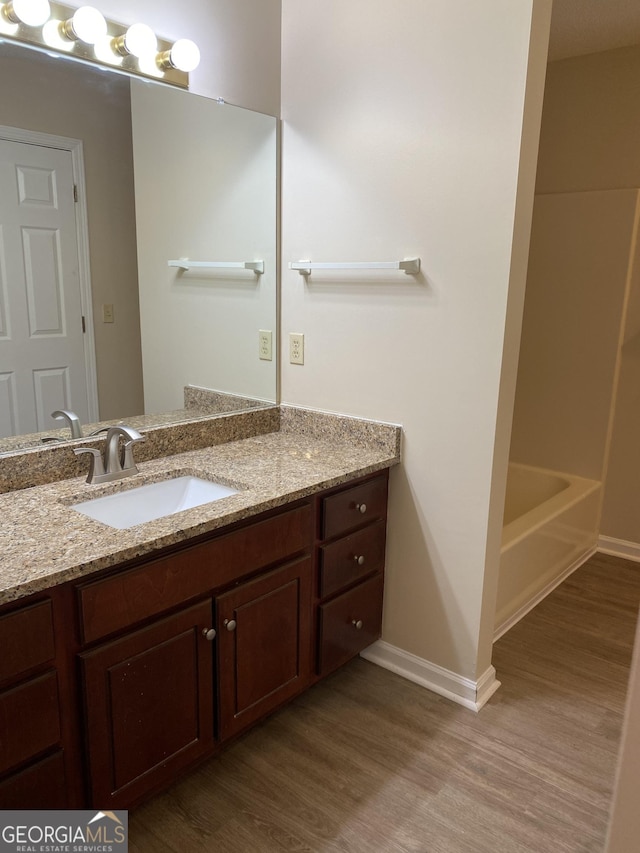 bathroom with vanity, baseboards, and wood finished floors