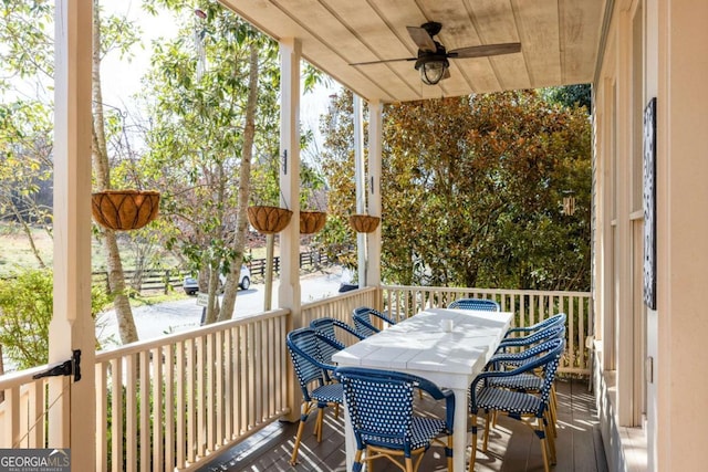 wooden deck with outdoor dining area and ceiling fan