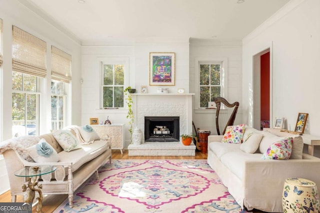 living area with a brick fireplace, wood finished floors, and crown molding