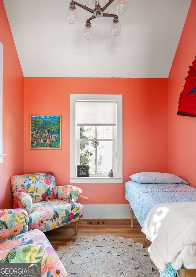 bedroom with vaulted ceiling, visible vents, baseboards, and wood finished floors