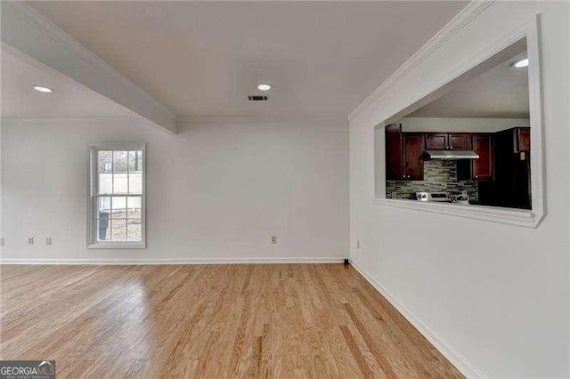 interior space featuring light wood finished floors, visible vents, baseboards, and ornamental molding