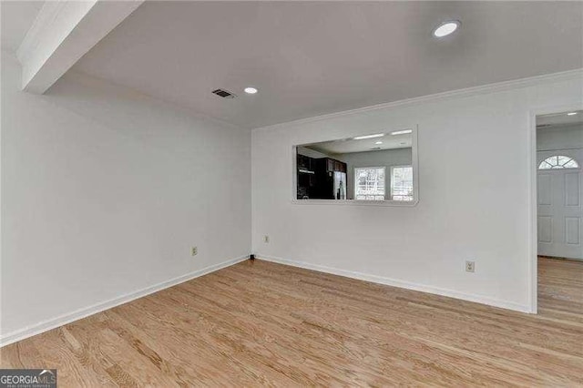 spare room featuring ornamental molding, wood finished floors, visible vents, and baseboards