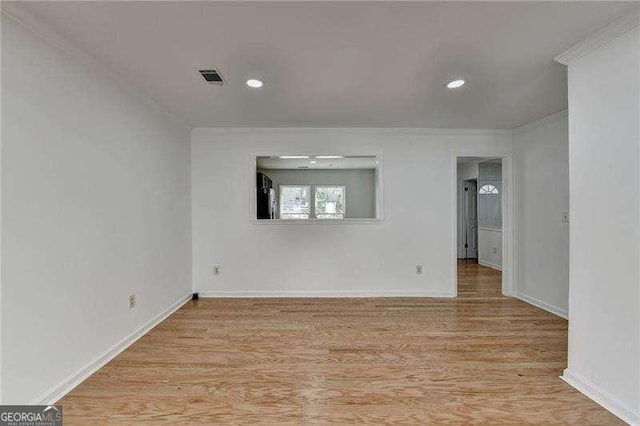 empty room featuring visible vents, wood finished floors, and ornamental molding