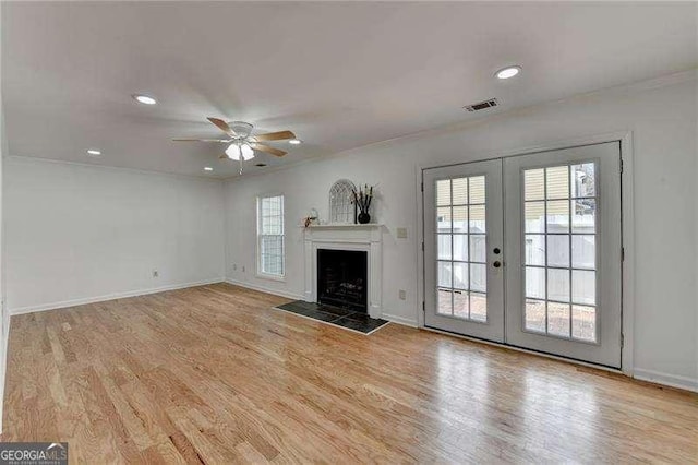 unfurnished living room with wood finished floors, visible vents, french doors, and a healthy amount of sunlight