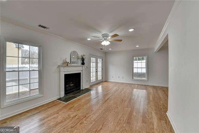 unfurnished living room with visible vents, wood finished floors, a fireplace, crown molding, and baseboards