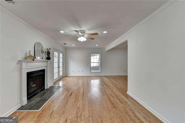 unfurnished living room with baseboards, ornamental molding, french doors, a fireplace, and wood finished floors