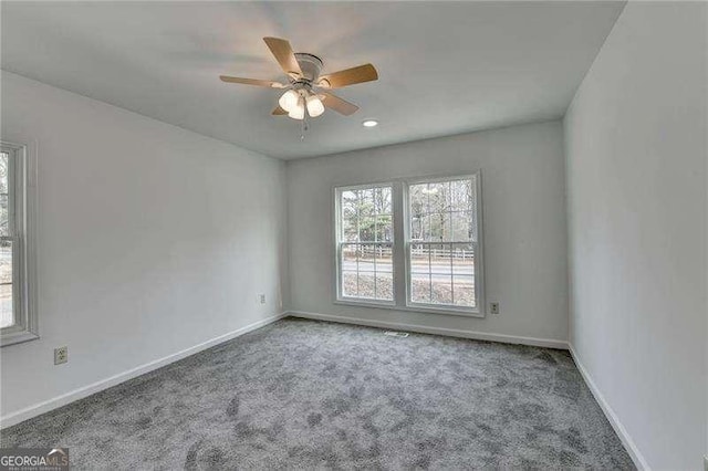 carpeted empty room featuring a ceiling fan and baseboards