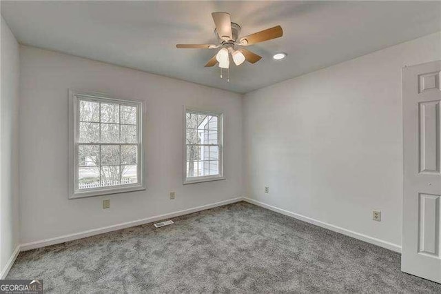 empty room featuring a ceiling fan, carpet flooring, visible vents, and baseboards