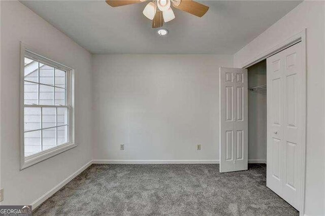 unfurnished bedroom with baseboards, carpet floors, a closet, and a ceiling fan