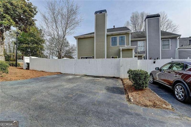 view of property exterior with a chimney and fence